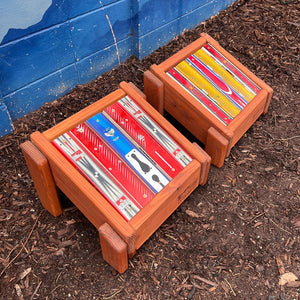 Two colorful ski top ottomans against a blue mountain mural.