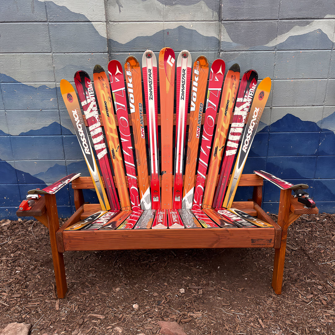 Wooden chair made from repurposed skis against a mountain-themed wall.