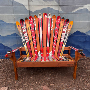 Wooden chair made from repurposed skis against a mountain-themed wall.