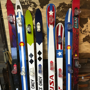 Collection of colorful shot skis with various designs on a wooden surface.