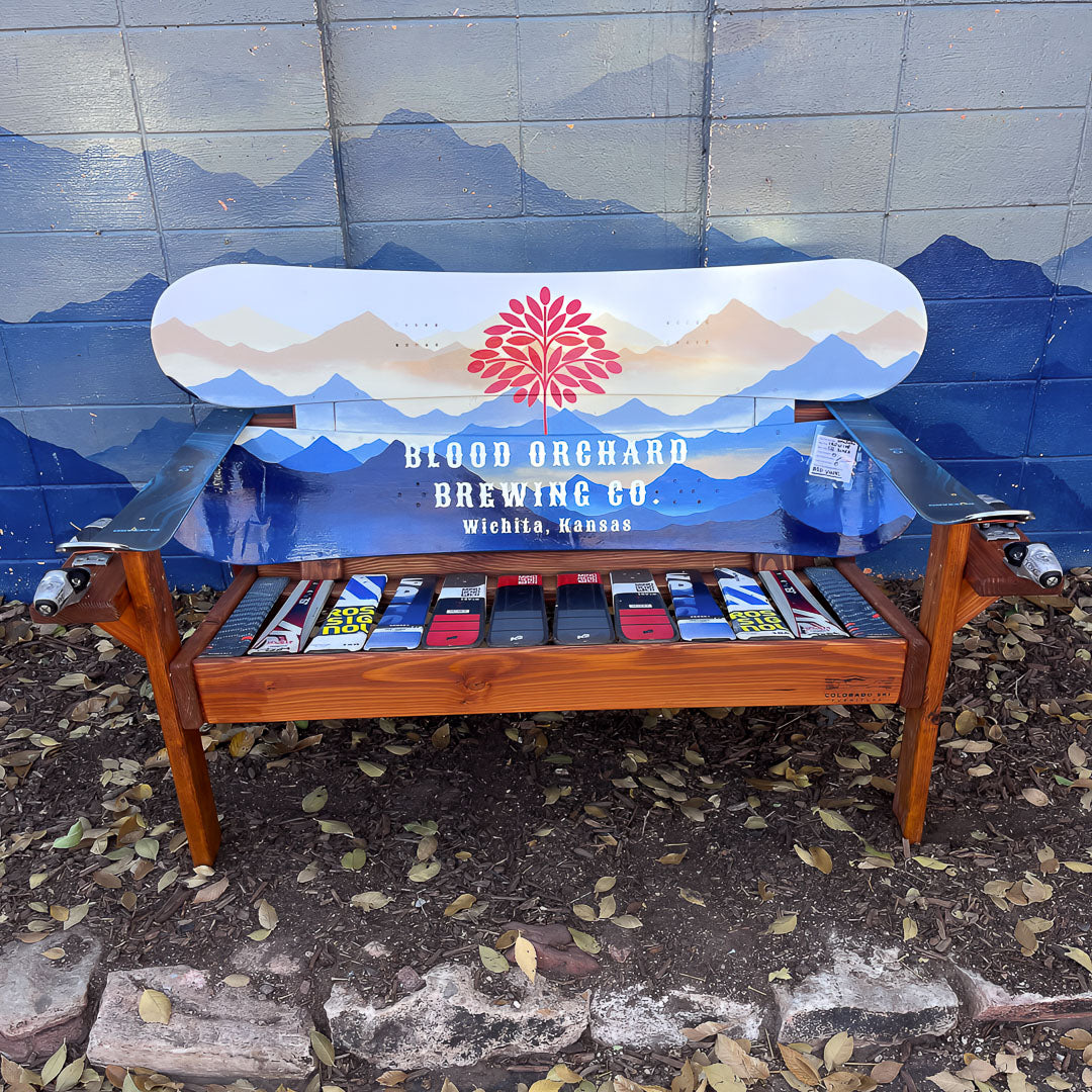 Custom branded Frontier Bench with Blood Orchard Brewing Co. logo and mountain scene on reclaimed snowboard backrest, mixed ski seat, and ski armrests on a wood frame