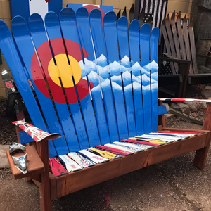 Colorful Adirondack chair with a Colorado flag design outdoors.